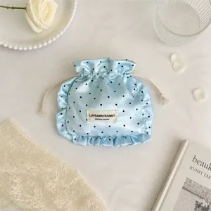 Chic blue satin polka dot drawstring pouch with ruffled edges for jewelry makeup storage.