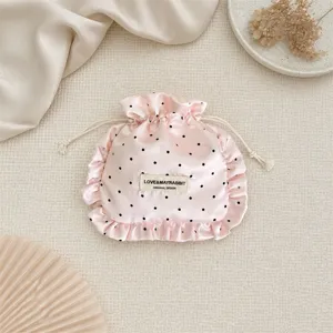 Detailed view of pink satin polka dot drawstring pouch with ruffles for jewelry and cosmetics.