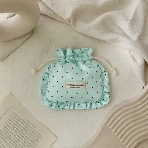 Detailed view of the mint green satin polka dot drawstring pouch with delicate ruffle edge.