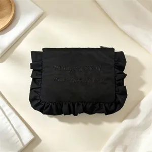 Detailansicht der schwarzen Nylon Kosmetiktasche mit süßem Rüschenrand und Stickerei.