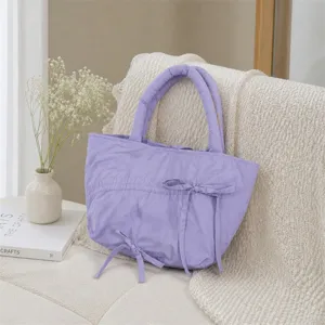 Vista dettagliata della borsa a mano plissettata viola con grazioso fiocco in ambiente estetico.