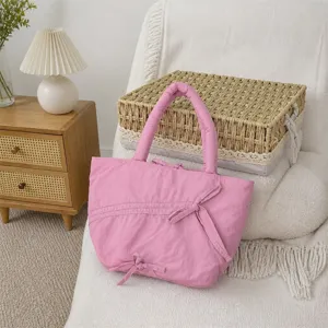 Dettaglio della borsa rosa plissettata con fiocchi carini in un ambiente domestico accogliente.