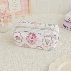 Close-up of a cute pink floral makeup bag with white lace trim and bow detail on textured desk.