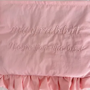 Rosa Nylontasche mit süßen Rüschen und feinen gestickten Buchstaben für Kosmetikartikel.