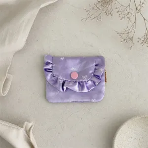Close-up detail of the purple satin ruffle coin purse with cute bow print and pink button.
