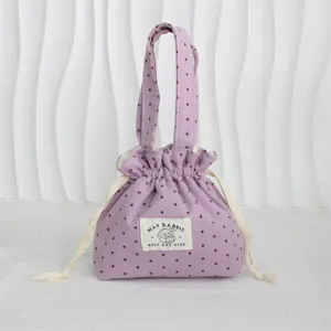 Detalle de la bolsa de tela morada con cordón, estampado de estrellas y etiqueta frontal mona.
