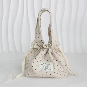 Bolso de mano con cordón de lona beige con estampado de estrellas marrones, etiqueta de conejo.