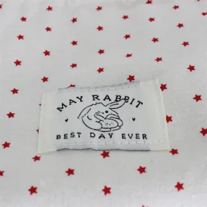 Primer plano detalle de tela blanca con estrellas rojas y etiqueta de marca para un lindo bolso.