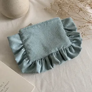 Corduroy cosmetic bag detail, soft blue ruffle storage pouch for daily makeup essentials.