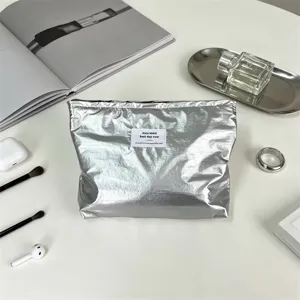 Dettaglio borsa cosmetica impermeabile lucida argento con finitura metallica ed etichetta.