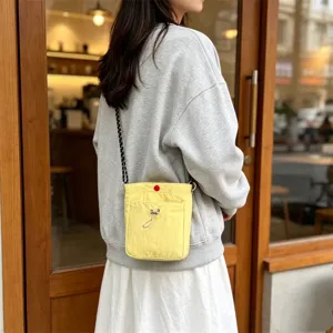 Detailaufnahme einer gelben Nylon-Minischultertasche im Alltagseinsatz mit feinem Gurt.