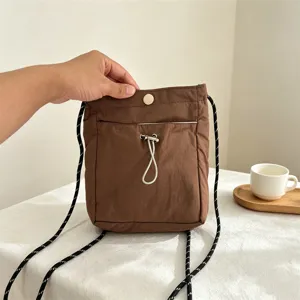 Braune Nylon Mini Umhängetasche Detail, lässige Handytasche mit Kordelzug und Trageriemen.