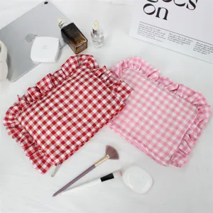 Detailopname van rood en roze geruite make-tasjes met volants, schattige cosmetische etui.