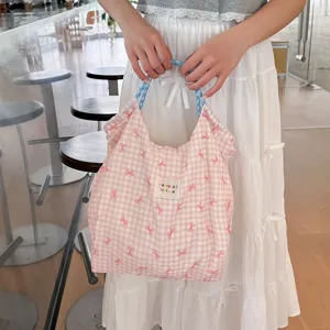 Détail de sac cabas en toile vichy rose, avec adorable imprimé nœud et poignée cordon bleu.