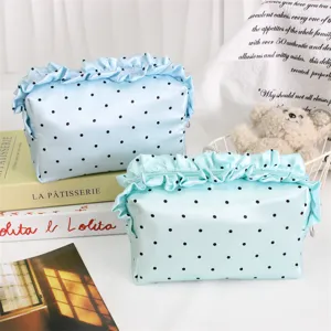 Detailansicht der blauen gepunkteten Satinkosmetiktasche mit Rüschen und Reißverschluss.