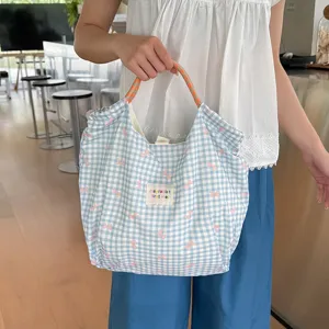 Vue détaillée de ce joli sac fourre-tout à carreaux bleus avec nœuds et cordon de serrage.