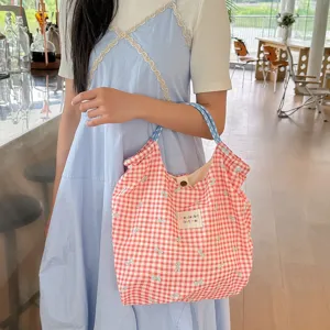 Vue détaillée du sac cabas en toile à carreaux rouges et blancs avec jolis nœuds bleus.