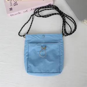 Nahaufnahme einer hellblauen Nylon-Mini-Umhaengetasche mit schwarz-weissem Seilriemen.