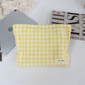 Detalle de la bolsa de maquillaje a cuadros amarillos, neceser de tela portátil para viaje.