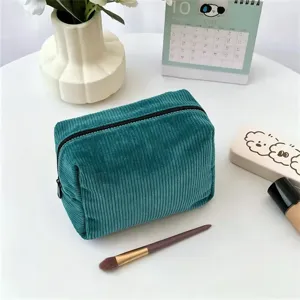 Dark green corduroy makeup bag detail, textured cosmetic storage pouch with zipper closure.
