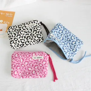 Leopard print zipper coin purse detail showing soft fabric, durable zipper, and handy wrist strap.