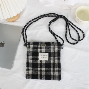Classic black and white plaid mini crossbody bag close-up, soft woolen fabric with shoulder strap.