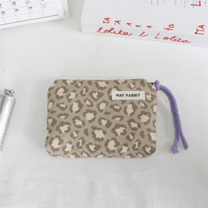 Close-up detail of stylish leopard print coin purse with purple wrist strap and fabric label.
