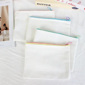 Detail shot of white canvas zipper pouches, minimalist solid color pencil cases for school.