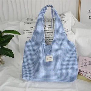 Close-up of blue and white gingham tote bag, casual shoulder bag featuring a cute woven label.
