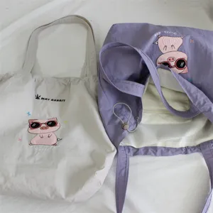 Vista detallada de bolsos tote casuales con bordado de cerdito y diseño de cordón.
