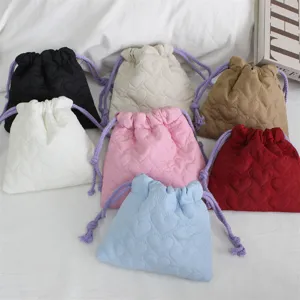 Détail de pochette matelassée cœur, sac de rangement souple et rembourré pour bijoux et pièces.