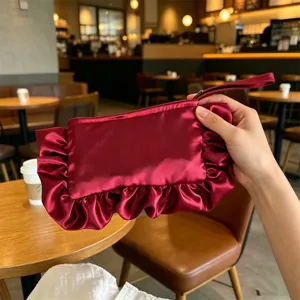 Vista detallada del bolso de mano de satén rojo con volantes, diseño plisado elegante.