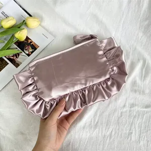 Detalle de bolso de mano de satén con volantes, elegante neceser malva plisado chic.