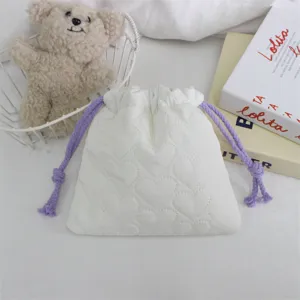 Gros plan de la pochette matelassée blanche en cœur avec cordons violets, sac de rangement.