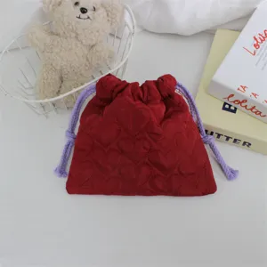 Vue détaillée de la pochette matelassée cœur avec cordons violets dans un décor esthétrique.