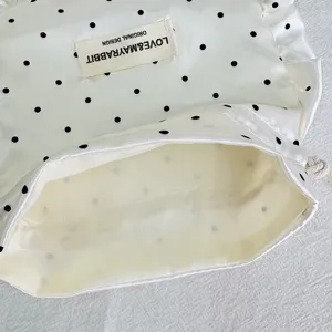 White satin polka dot drawstring pouch detail, delicate ruffle edge and cute design.