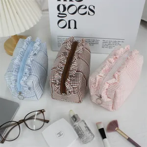 Detailopname van een schattige geplooide stoffen cosmeticatas met ruitjes en handige ritssluiting.