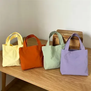 Detailed shot of colorful mini nylon tote bags displayed neatly on a wooden desktop.