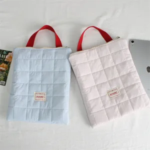 Quilted laptop sleeve with red handle, soft protective tablet storage bag for travel detail.