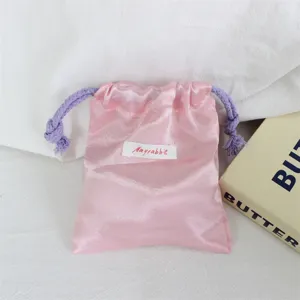 Roze satin trekkoord sieradenzakje detail opname met zachte stof textuur en koord.