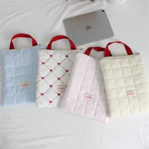 Soft quilted laptop sleeve and tablet storage bag with portable handle for daily travel use.