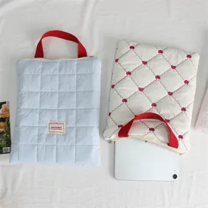 Quilted laptop sleeve detailed view, soft padded tablet storage bag with durable handles.