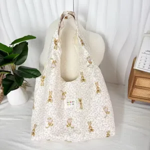 Detailed view of cream fabric hobo bag with cute rabbit print, soft shoulder strap design.