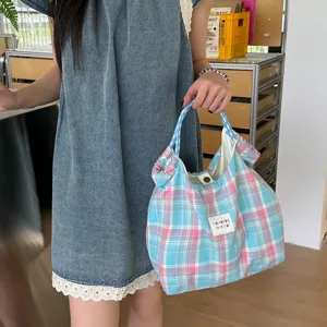 Vue détaillée du sac à main en tissu à carreaux bleus et roses, montrant la texture douce.