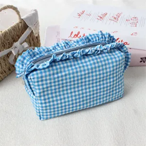 Detailansicht einer blau-weißen Vichy-Karos Kosmetiktasche mit Rüschen und Reißverschluss.