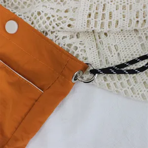 Nahaufnahme Detail der orangen Nylon Mini Umhaengetasche mit Metallring und Kordel.