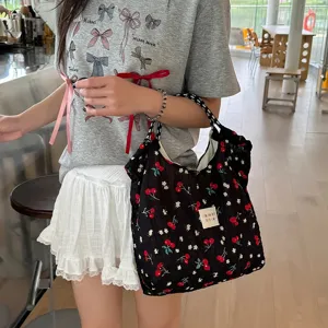 Vue détaillée du sac épaule noir en mousseline à motif cerise avec cordon de serrage.