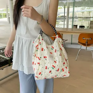 Gros plan détaillé du sac porté épaule élégant à motif cerise et texture froissée.