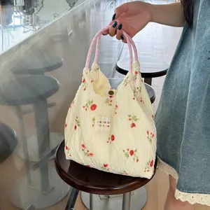Vue de détail du sac à main en tissu à fleurs avec anses vichy roses et cordon de serrage.