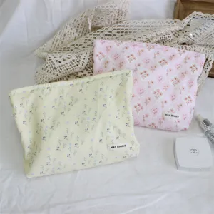 Detailed close-up of cute floral corduroy cosmetic pouches in yellow and pink with lace background.